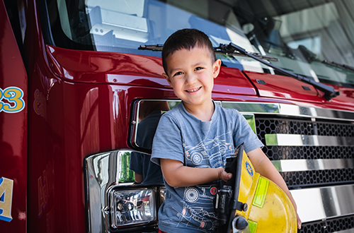 Child standing in front of a fire engine